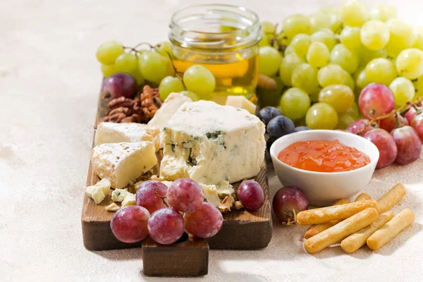 Сырная доска, свежий виноград и мед на белом фоне — стоковое фото