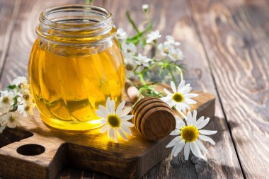 koyu ahşap bir masa portre üzerinde taze çiçek bal ile jar