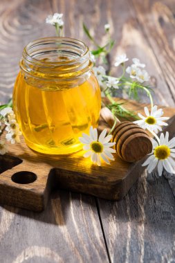 koyu ahşap bir masa, dikey olarak taze çiçek bal ile jar