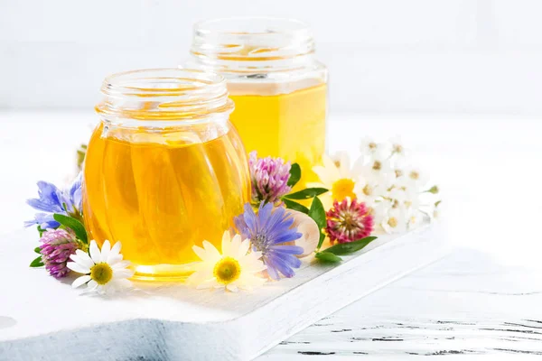 Pots avec du miel de fleur sur fond blanc en bois, gros plan — Photo