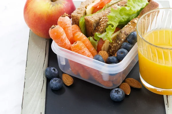 Lunch box with sandwich of wholemeal bread on blackboard — Stock Photo, Image