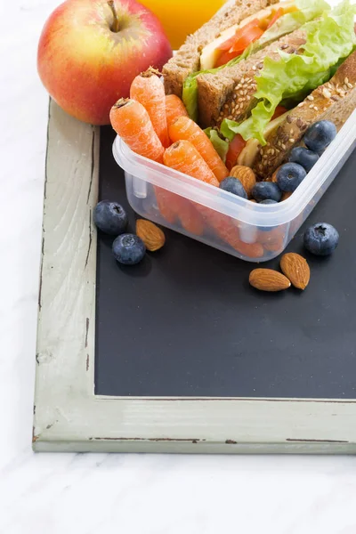 Lunchbox mit Sandwich aus Vollkornbrot auf Tafel — Stockfoto