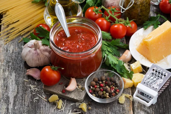 Molho de tomate e ingredientes em um fundo de madeira — Fotografia de Stock