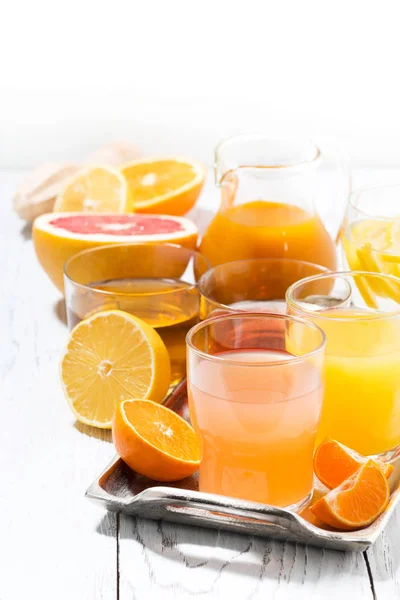 Assortment of fresh citrus juices on white table, vertical — Stock Photo, Image