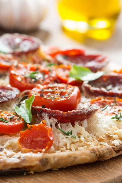 Pezzo di pizza con salame e pomodori su una tavola di legno — Foto Stock