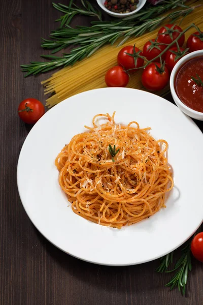 Spaghete cu sos de roșii și ingrediente pe o masă de lemn — Fotografie, imagine de stoc