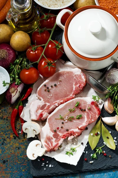 Two pieces of raw pork and fresh ingredients for preparation — Stock Photo, Image