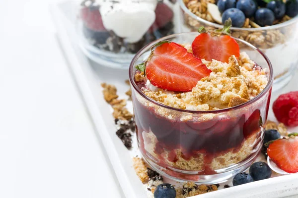 Postres dulces con bayas frescas en vasos sobre mesa blanca —  Fotos de Stock