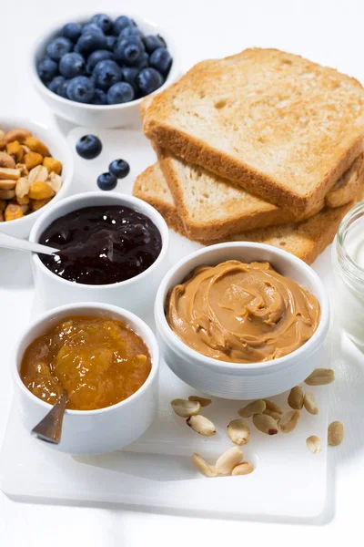 Peanut butter, jams and toasts for breakfast, vertical closeup — Stock Photo, Image