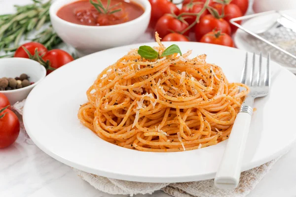 Pasta met tomatensaus op een plaat en ingrediënten — Stockfoto