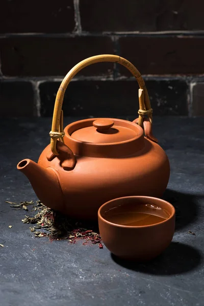 Brown ceramic teapot and cup of tea on a dark background — Stock Photo, Image