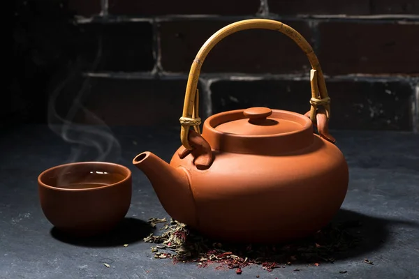 Brown ceramic teapot and cup of tea on a dark background — Stock Photo, Image