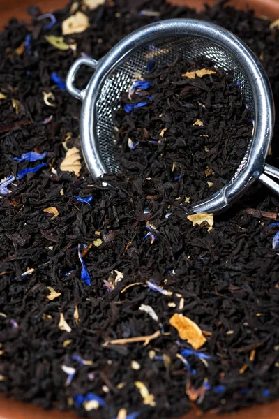 Suchý černý čaj s aromatickými bylinkami v cedníku, vertikální — Stock fotografie