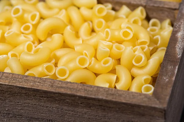 Dry pasta in a wooden box, selective focus — Stock Photo, Image