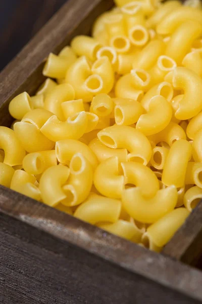 Dry pasta in a wooden box, vertical selective focus — Stock Photo, Image