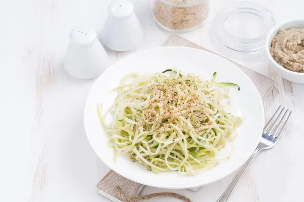 Teller vegetarische Pasta mit Zucchini und Nüssen auf weißem Tisch — Stockfoto