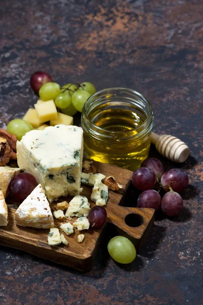 Käseplatte, Früchte und Honig auf dunklem Hintergrund, senkrecht — Stockfoto