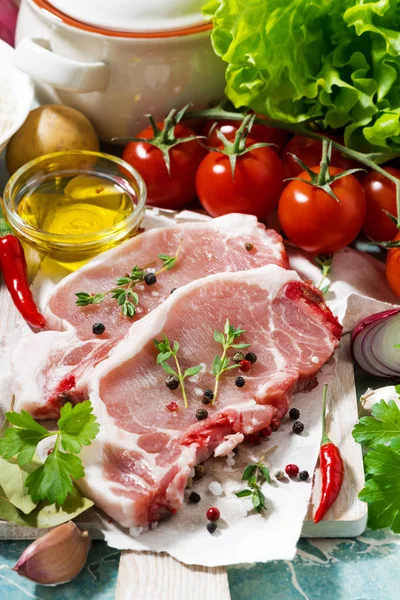 Two pieces of pork on a cutting board and fresh foods, vertical — Stock Photo, Image