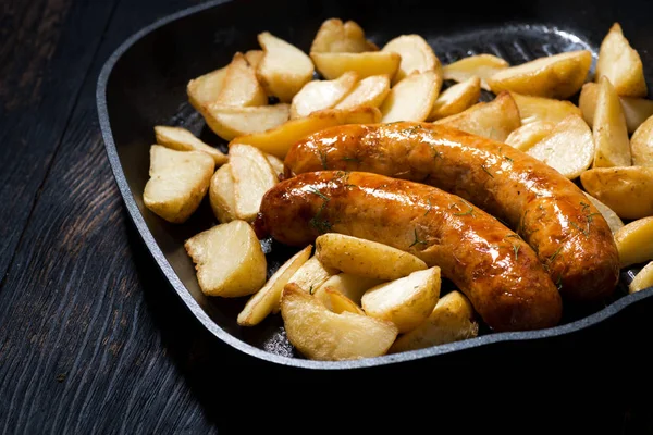 Saucisses de porc frites avec pommes de terre dans une poêle — Photo