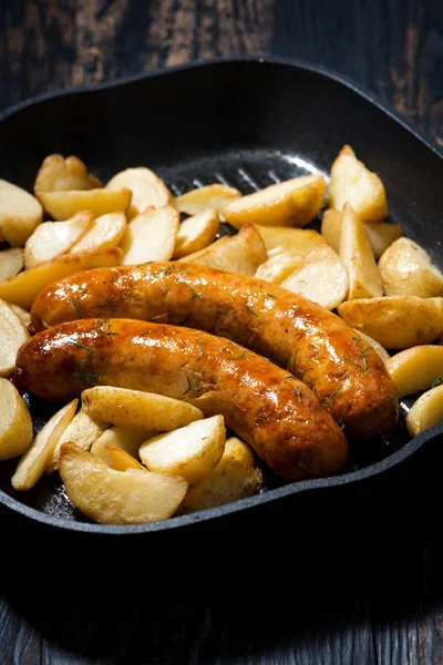 Fried pork sausages with potatoes in frying pan, vertical — Stock Photo, Image