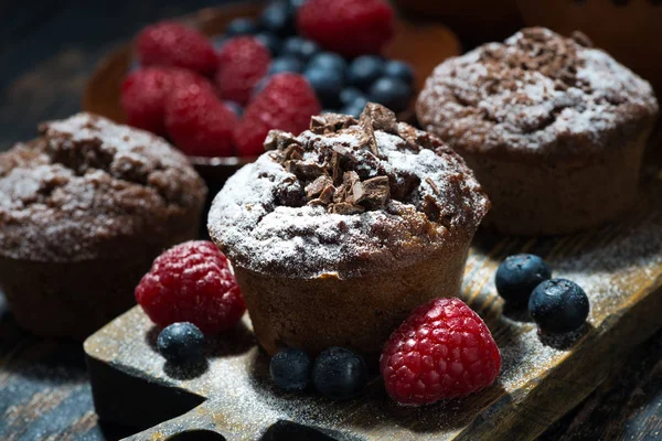 Muffins de chocolate e bagas frescas no tabuleiro de madeira — Fotografia de Stock