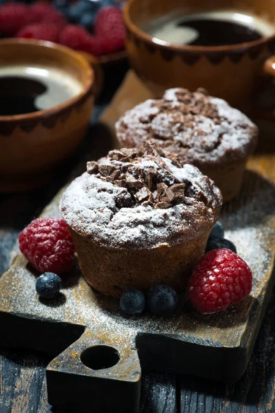 Muffins de chocolate e bagas frescas em tábua de madeira, vertical — Fotografia de Stock