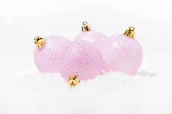 Bolas de Navidad de color rosa festivo en la nieve sobre un fondo blanco — Foto de Stock