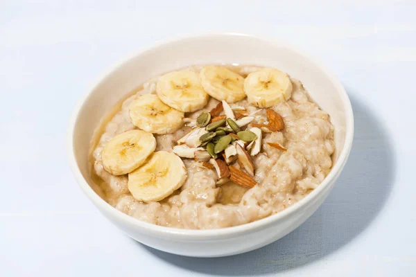 Tigela de aveia com banana, mel e nozes na mesa — Fotografia de Stock