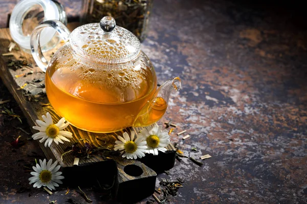 Chamomile tea in a glass teapot and dark background, top view — Stock Photo, Image
