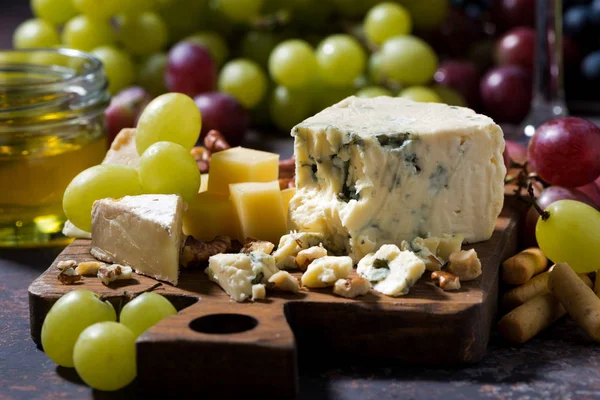Käsebrett und Trauben auf dunklem Hintergrund — Stockfoto