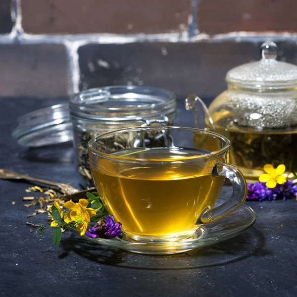 Glass cup of fresh tea with aromatic herbs on a dark background — Stock Photo, Image