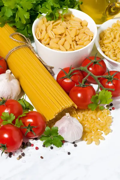 Спагетти, помидоры и свежие ингредиенты на белом столе — стоковое фото