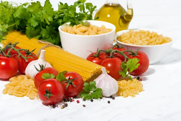 Spaghetti, tomatoes and fresh ingredients on a white table — Stock Photo, Image