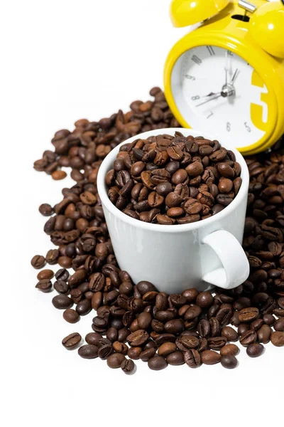 Taza con granos de café y reloj despertador amarillo sobre fondo blanco — Foto de Stock