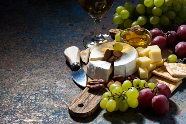Закуски, вино и камамбер и темный фон — стоковое фото
