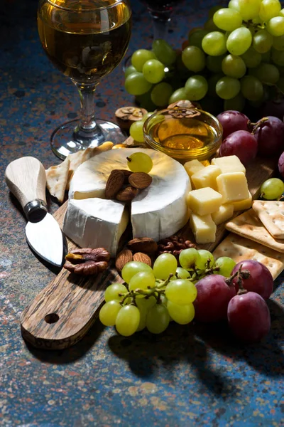 Lanches, vinho e camembert em um fundo escuro, vertical — Fotografia de Stock