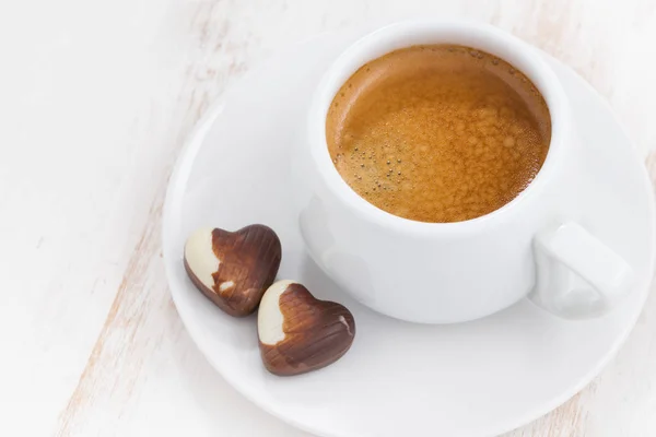 Cuori di cioccolato e espresso su sfondo bianco in legno — Foto Stock