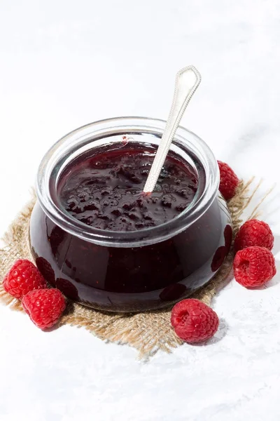 Raspberry jam in a glass jar on white background, vertical — Stock Photo, Image
