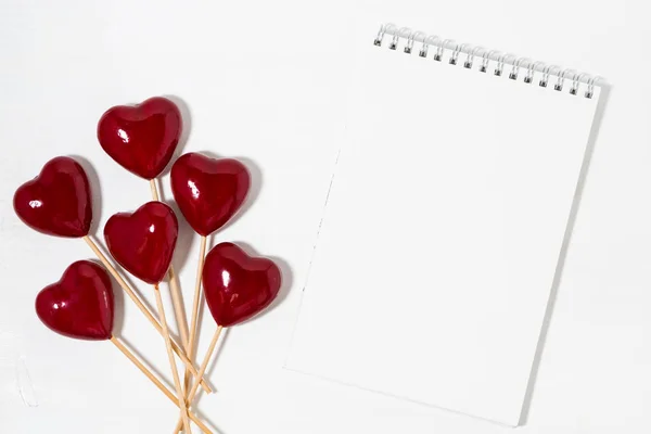 Coeurs décoratifs sur bâtons et bloc-notes sur fond blanc — Photo