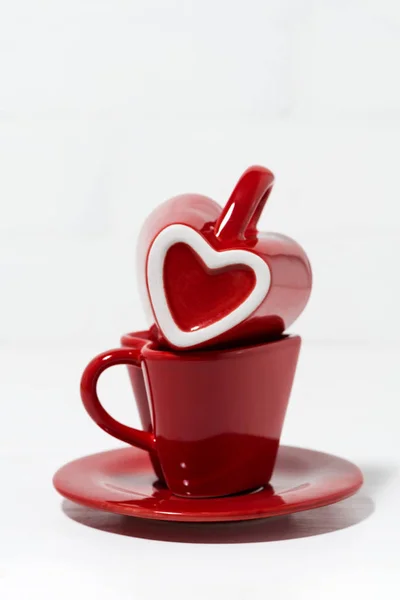 Red coffee cups with hearts on white background, vertical — Stock Photo, Image