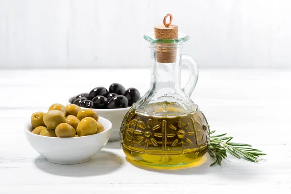 Bottle with olive oil and bowls with olives — Stock Photo, Image