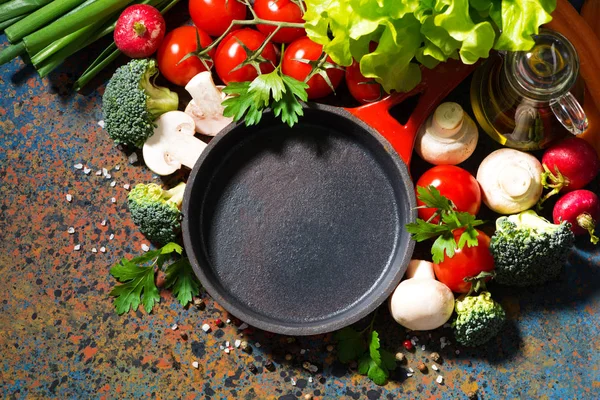 Empty cast iron skillet and fresh organic vegetables, top view — Stock Photo, Image