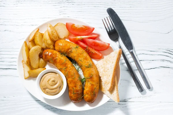 Fried sausages with potatoes and mustard on white table — Stock Photo, Image