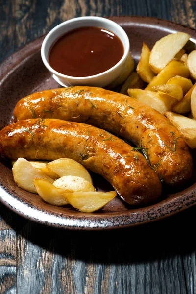 Fried pork sausages with potatoes and ketchup, vertical closeup — Stock Photo, Image