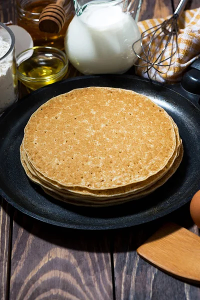 Traditional thin pancakes in a frying pan, vertical — Stock Photo, Image