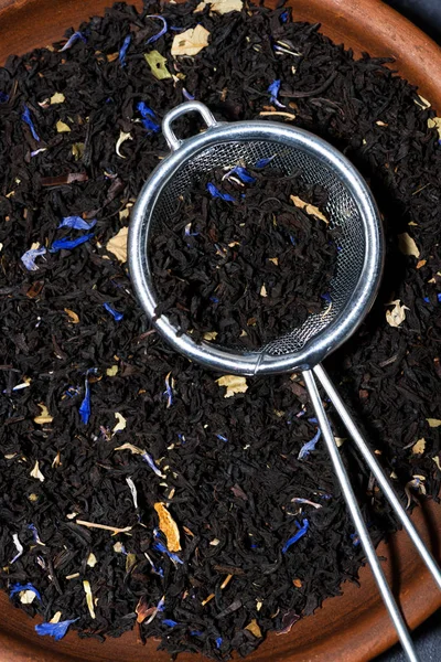 Suchý černý čaj s bylinkami v cedníku, vertikální pohled shora — Stock fotografie