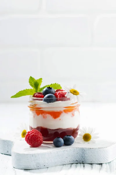 Dessert with jam, cream and fresh fruit in a glass jar, vertical — Stock Photo, Image