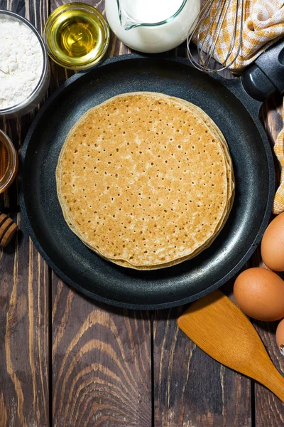 Traditional thin pancakes in a frying pan and ingredients — Stock Photo, Image