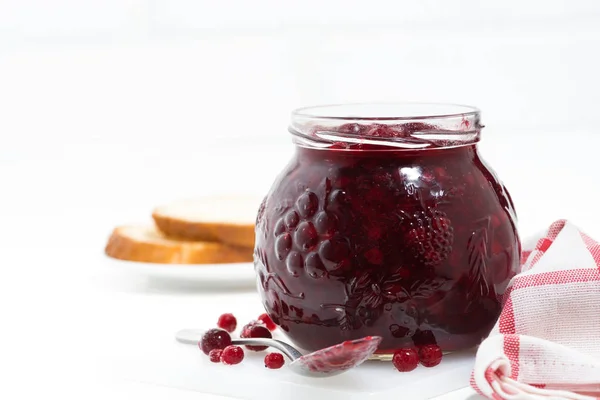 Jar of cranberry jam on a white table, closeup — Stock Photo, Image
