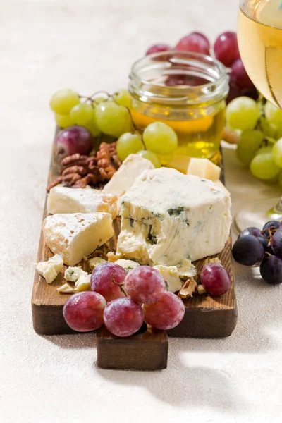 Cheeseboard, grapes and wine on a white background, vertical — Stock Photo, Image